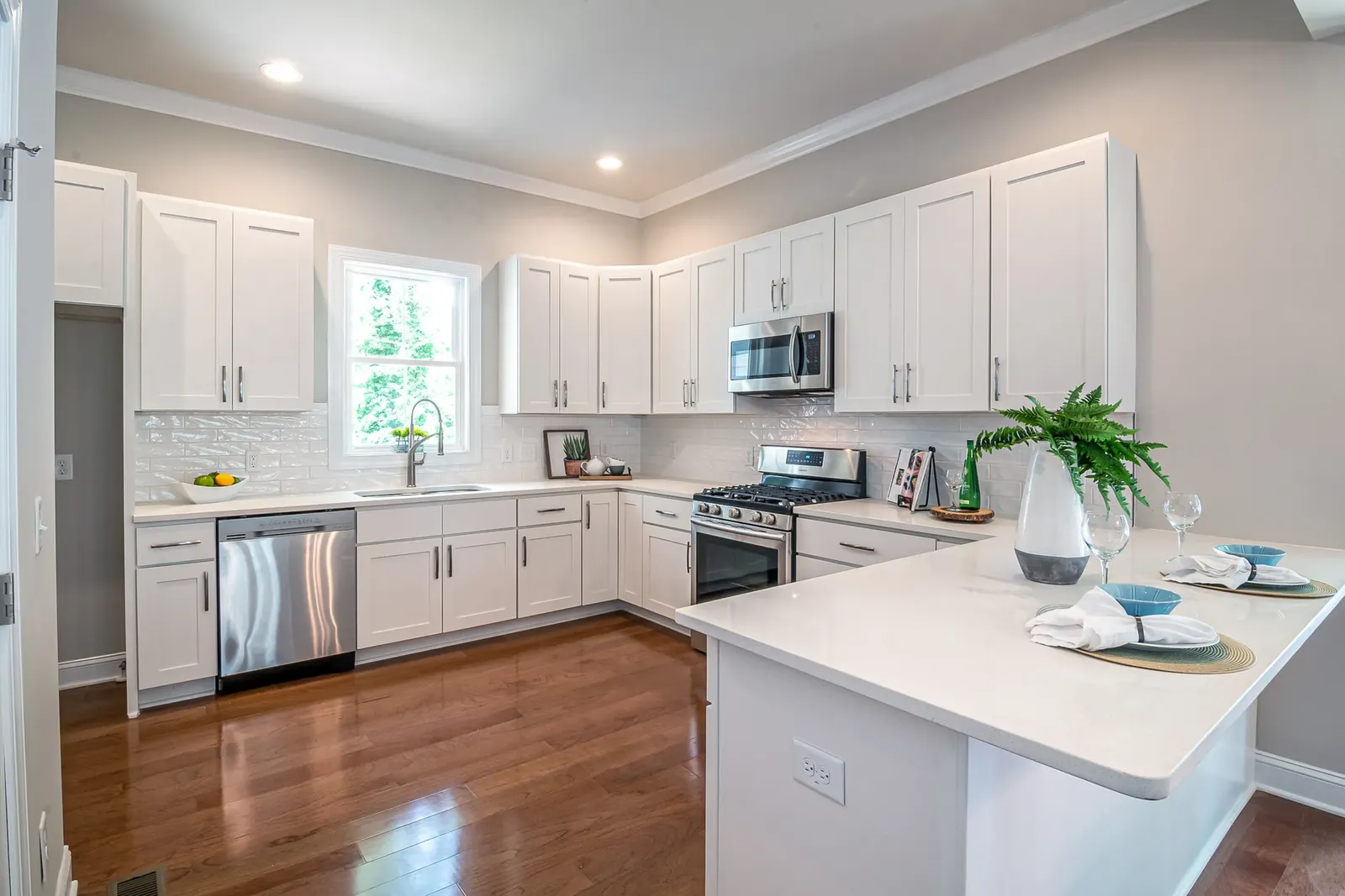 Bright contemporary kitchen with white cabinetry, tile backsplash, and wood flooring