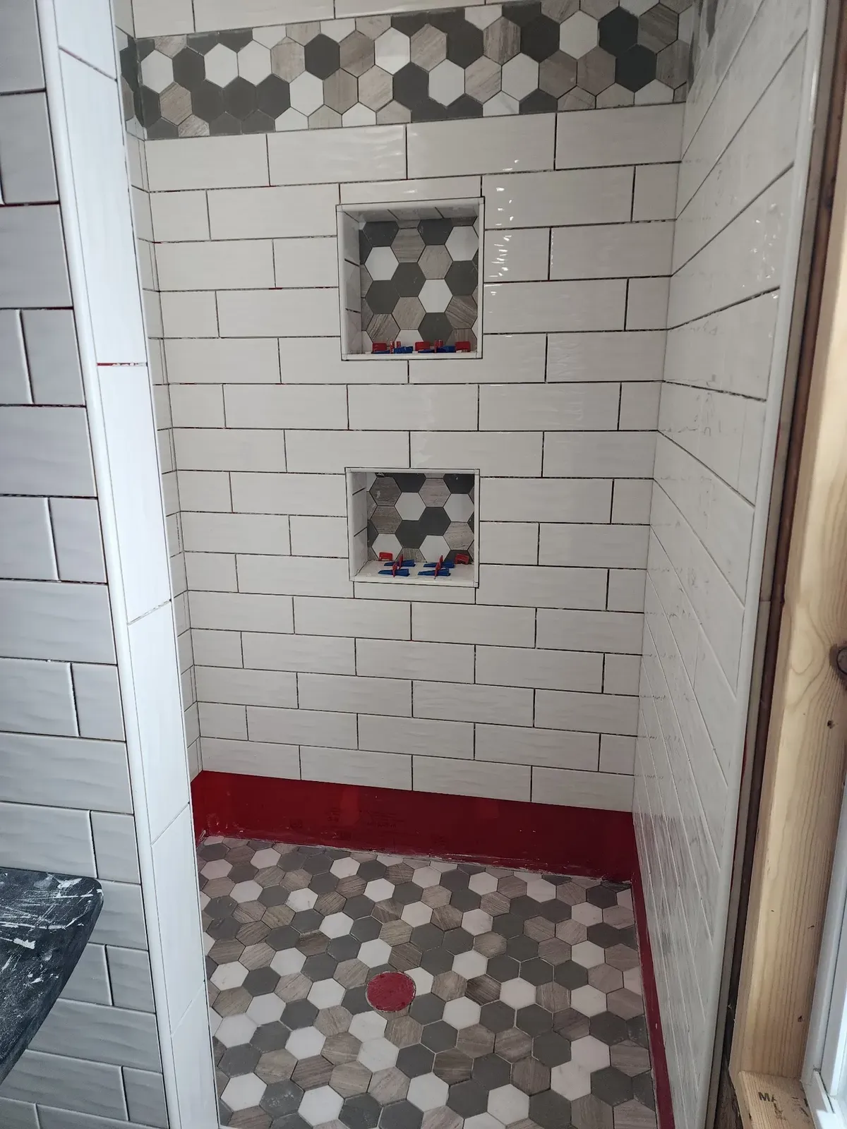 Subway tile and hex-accent niches during the cabin shower installation