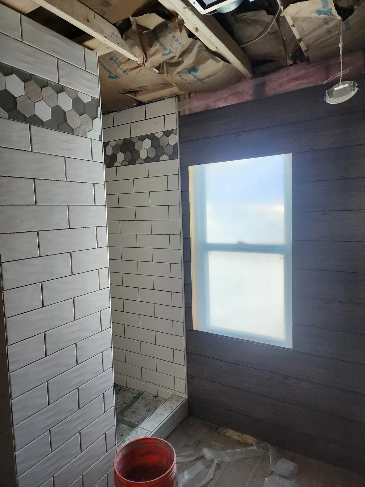 Shower tile installation around the window during the cabin remodel