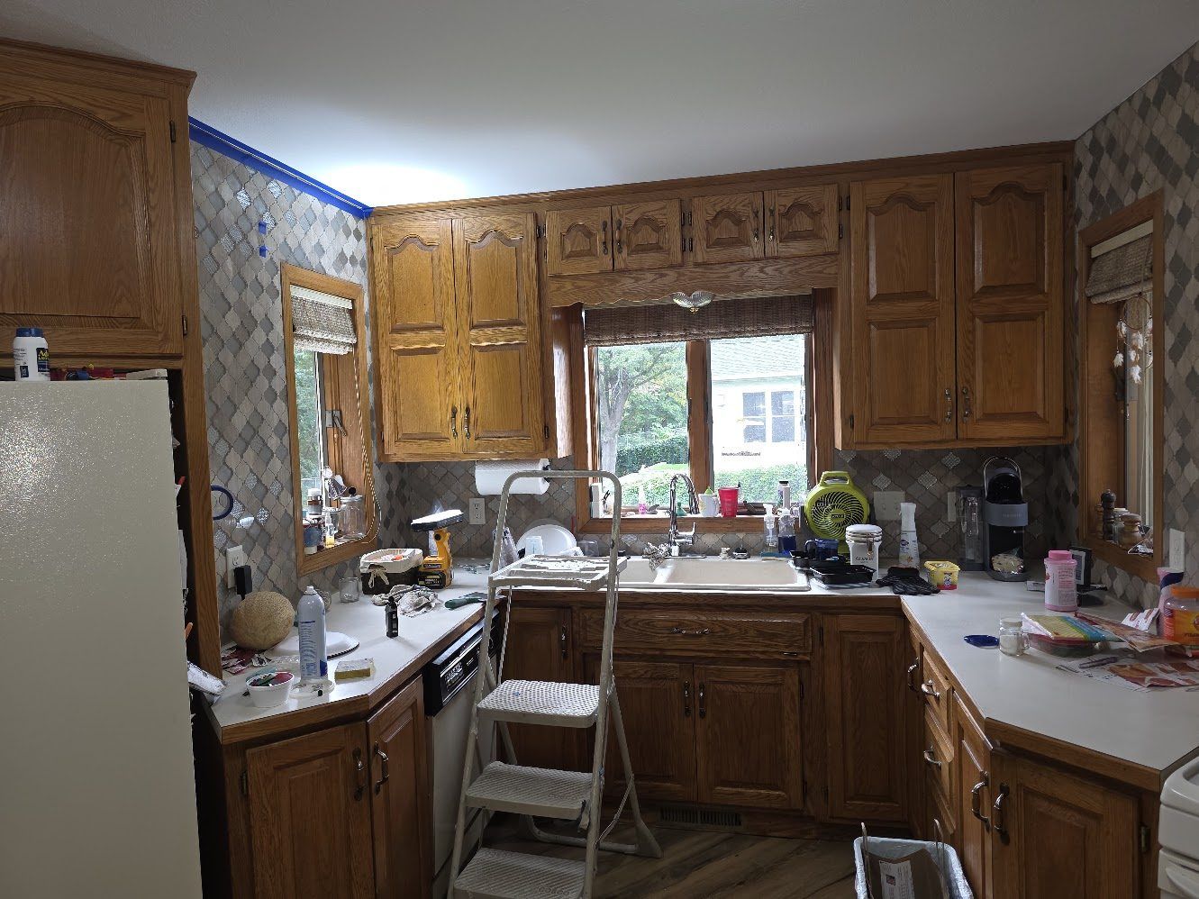 Kitchen prepared for painting with blue painter's tape along the ceiling