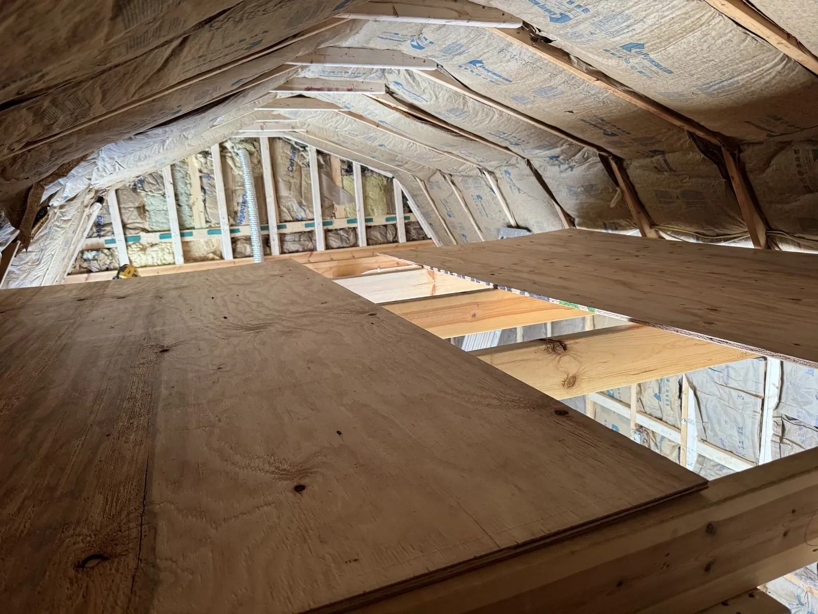 Plywood loft decking going down over the framing beneath the insulated roof