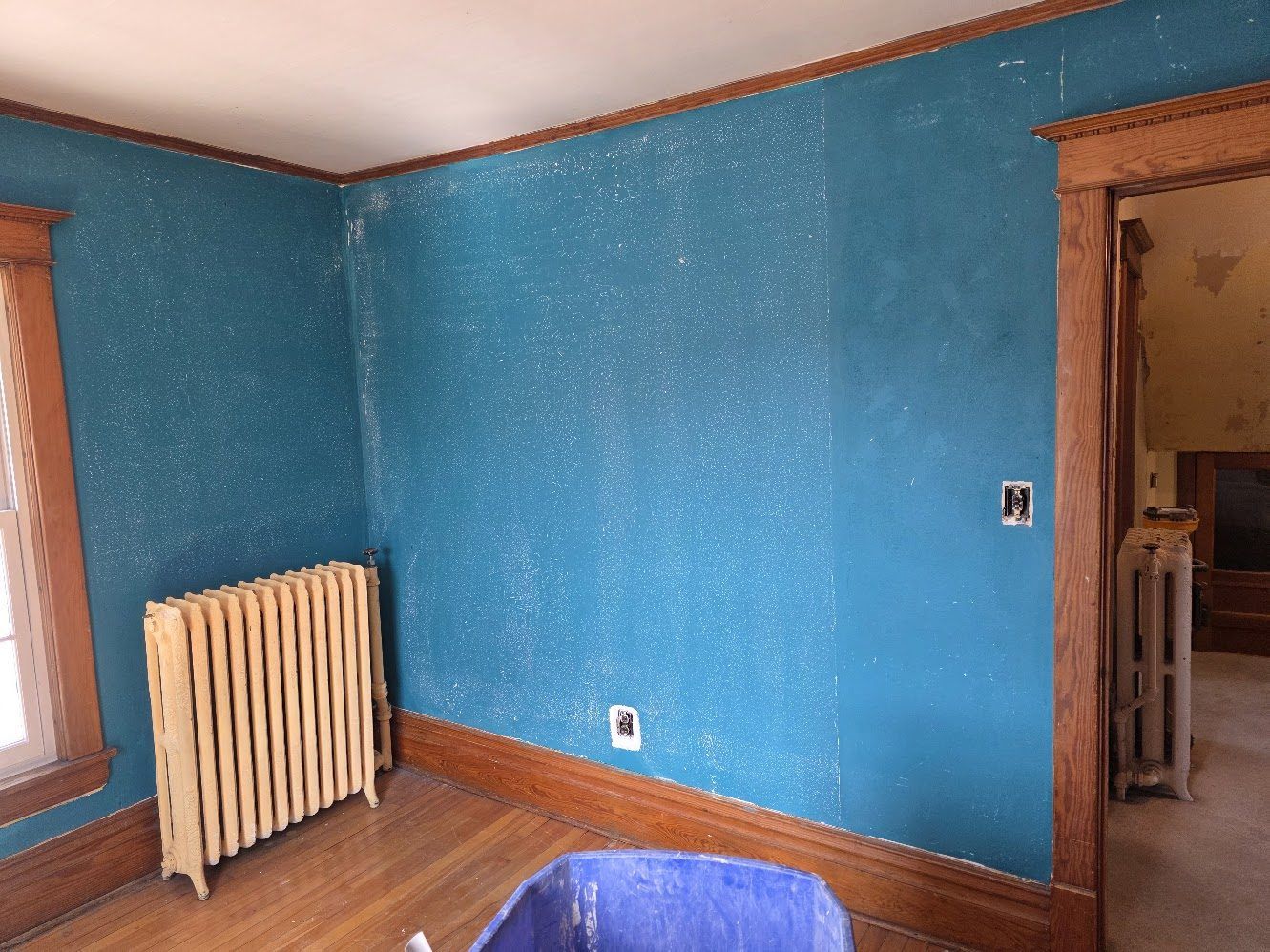 Bedroom walls during the painting stage, with the floor protected