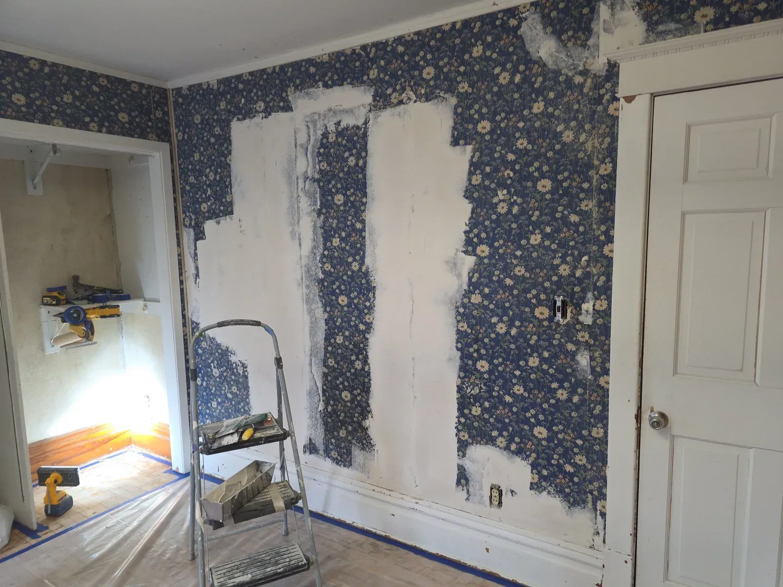 Wallpaper being removed from an interior wall during renovation