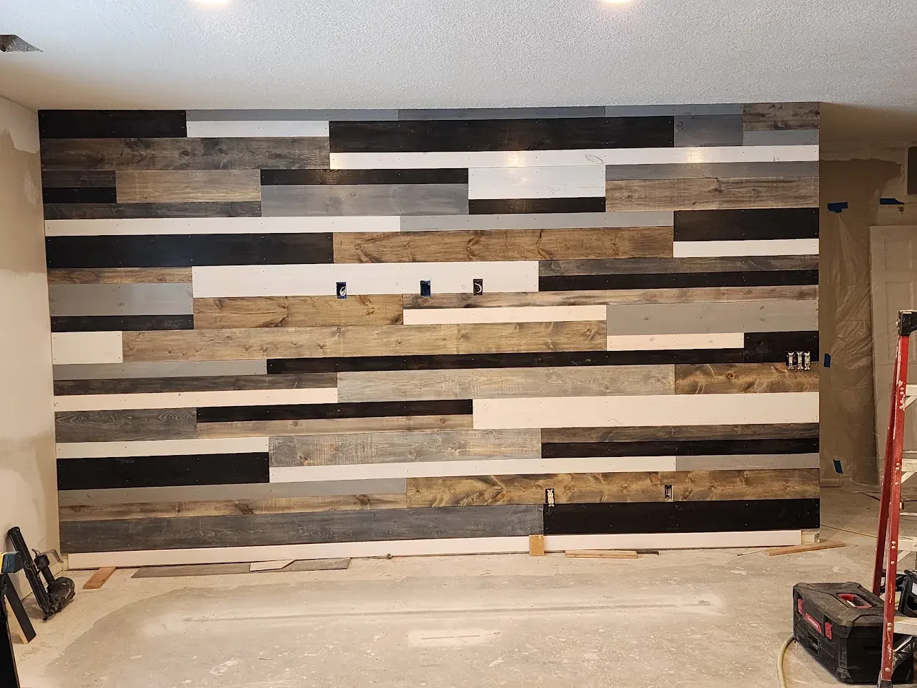 Reclaimed wood being installed on the basement accent wall