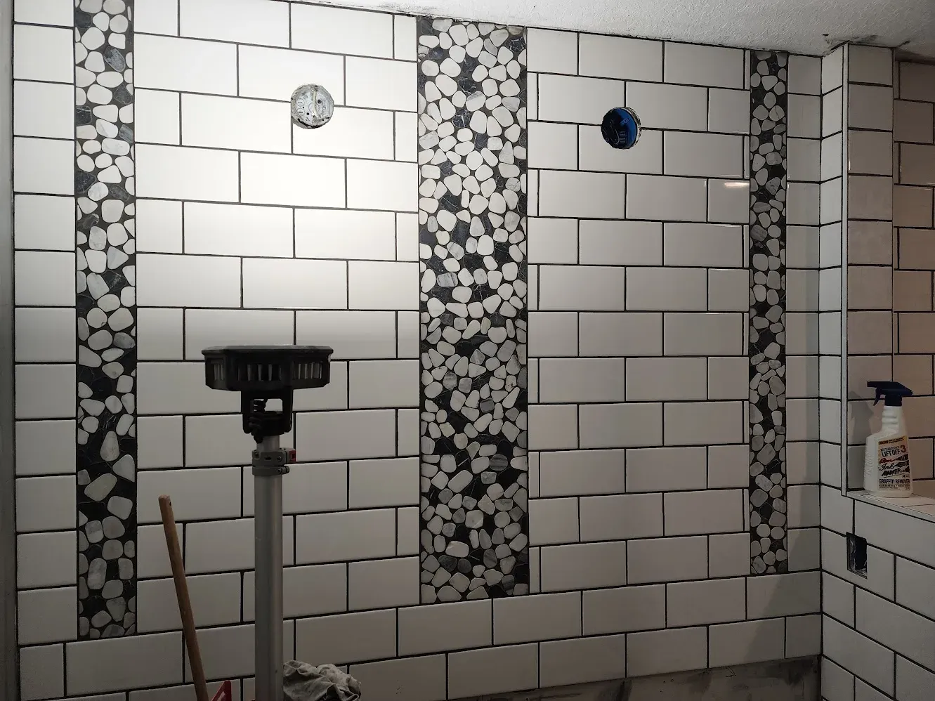 Subway tile walls with pebble-accent strips during the walk-in shower installation