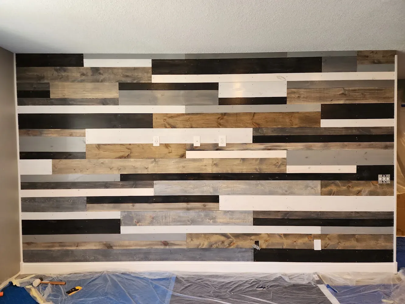 Reclaimed-wood accent wall during installation in the basement remodel