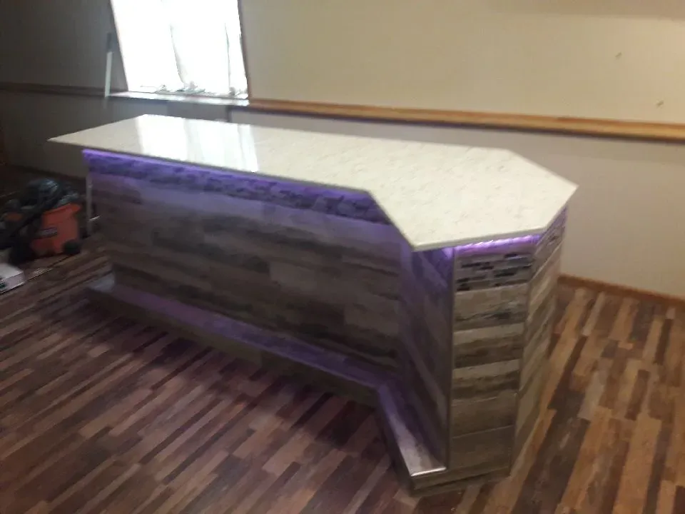 Completed custom basement bar with mosaic tile surround and accent lighting