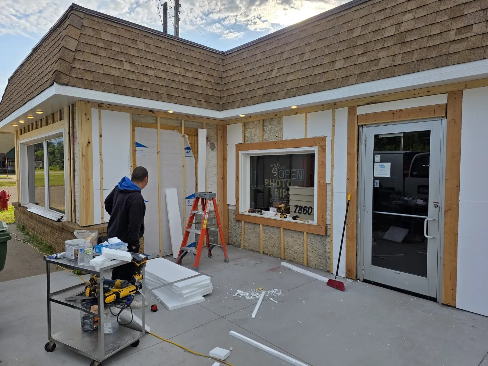 Worker cutting exterior materials beside the exposed storefront framing