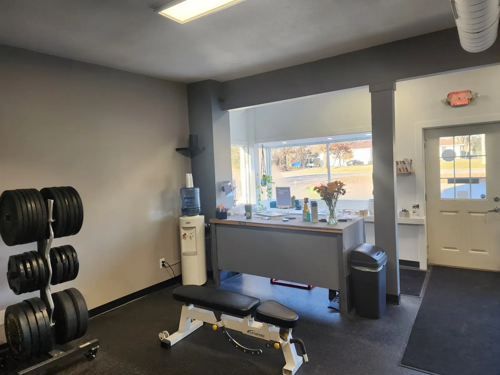 Finished exercise area near the gym entrance with a dumbbell rack and bench
