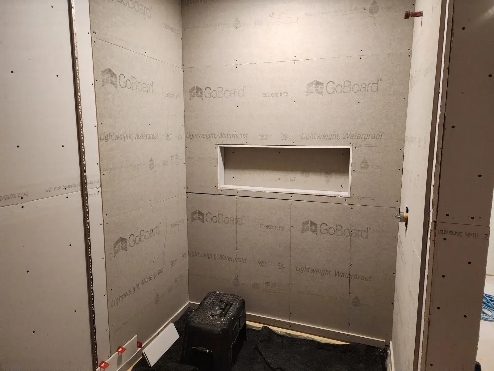 Walk-in shower lined with waterproof backer board and a recessed niche