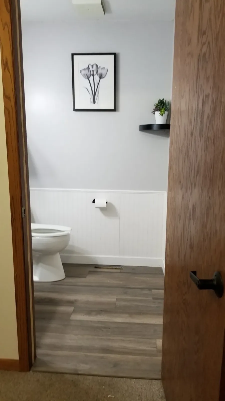 Finished church powder room viewed through the doorway with new beadboard, flooring, and paint
